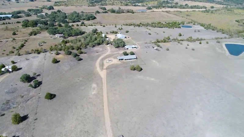 Aerial view of a rural property with open fields and a pond