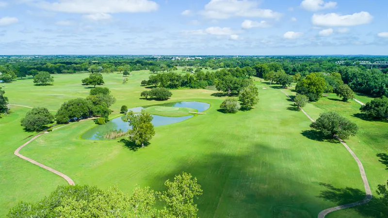 Aerial view of a country club golf course, lake, and tree-lined fairways