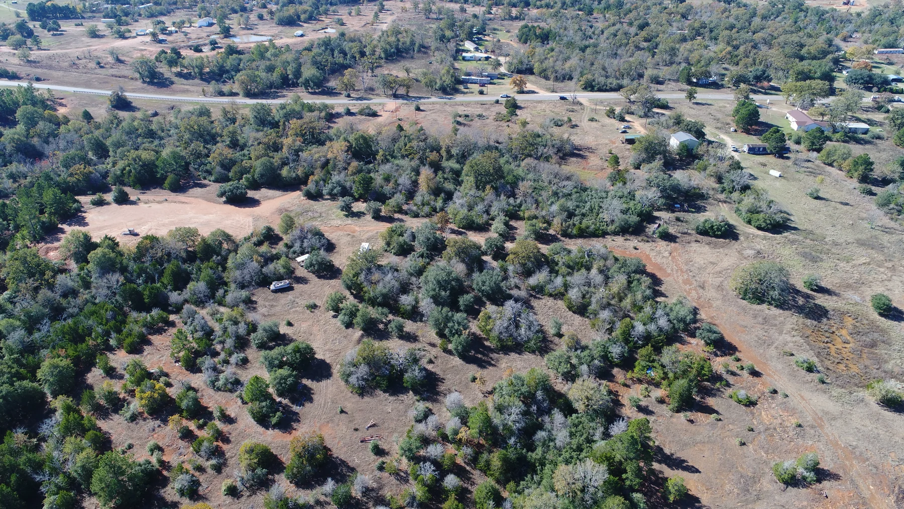 Drone view of rural land, mature trees, open spaces, and surrounding properties